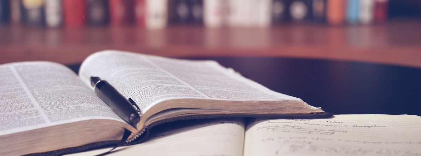 Open books with pages fanned out on a wooden desk